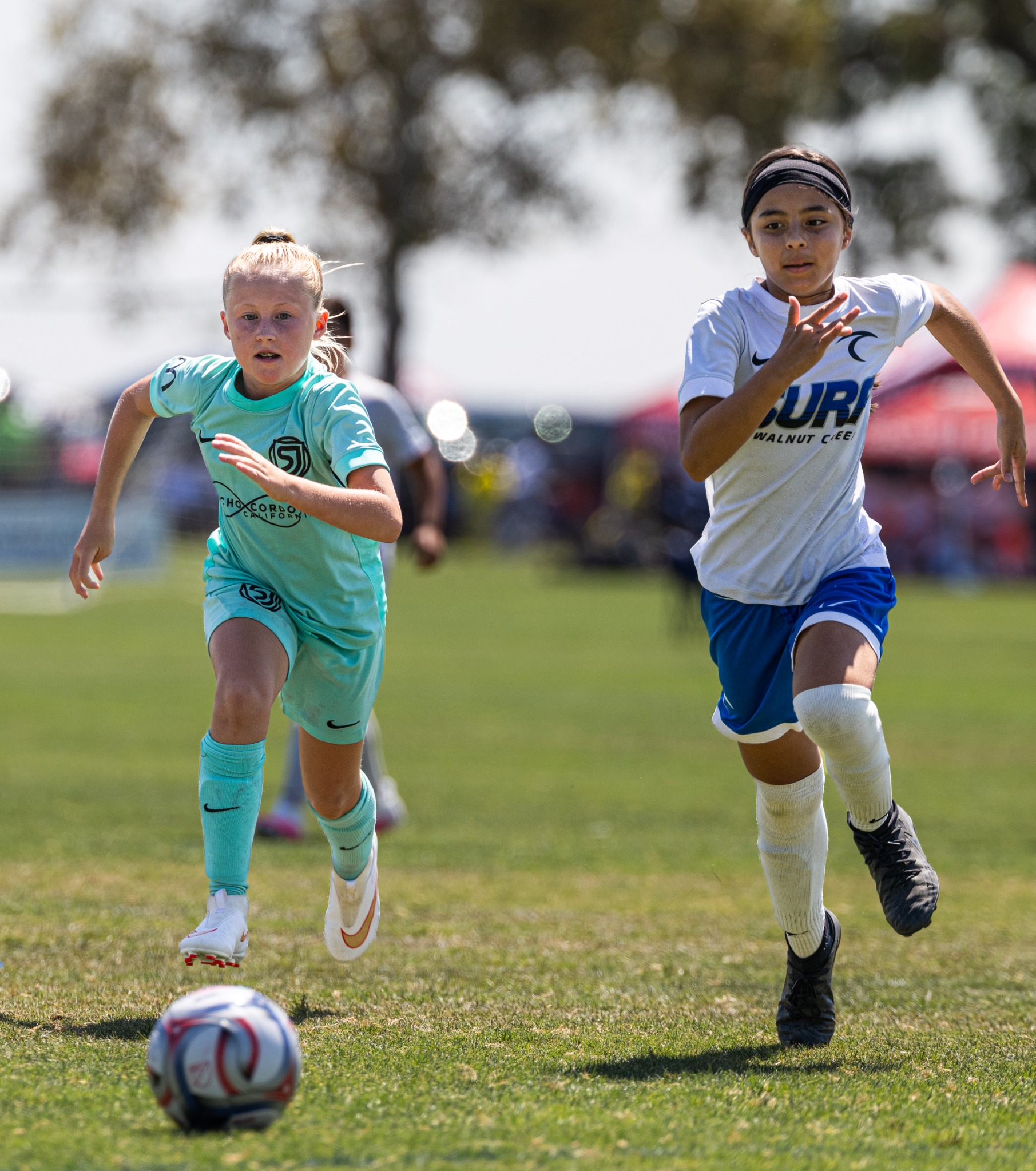 Two youth soccer players racing toward the ball