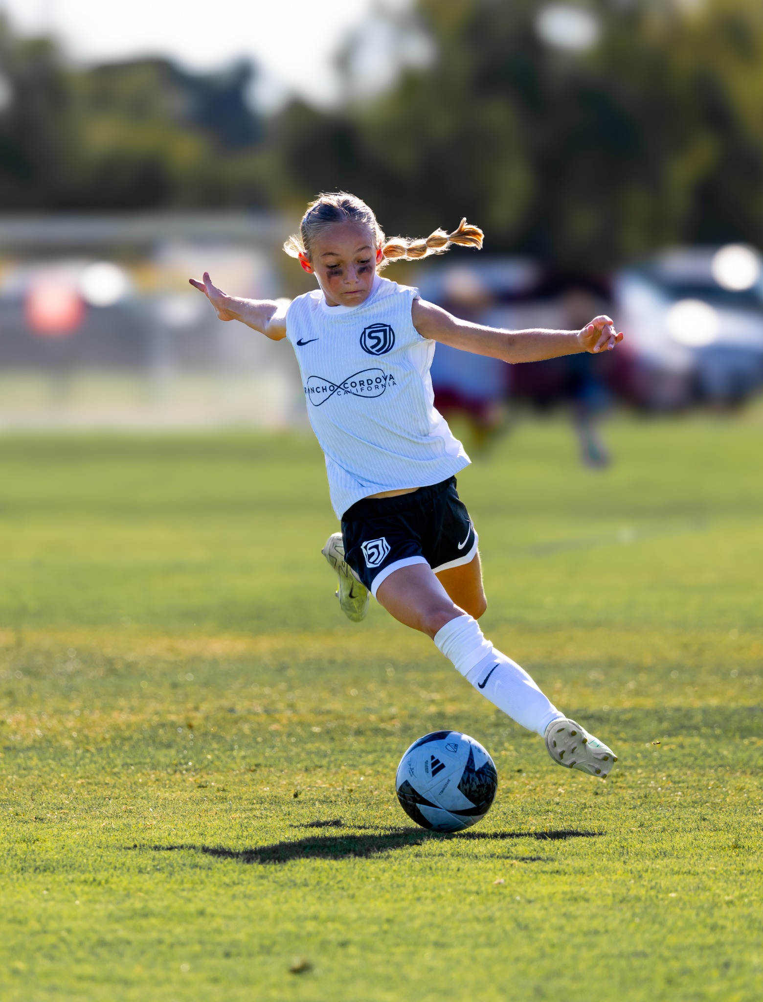 Youth soccer player striking the ball in bright backlight
